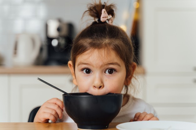 niña comiendo en un tazón negro
