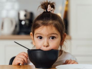 niña comiendo en un tazón negro