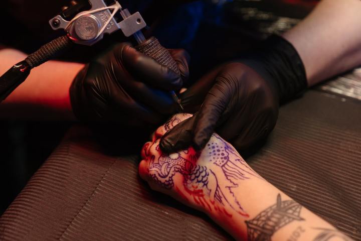 persona tatuándose la mano