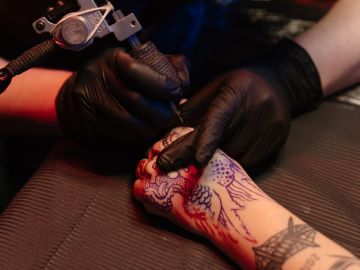 persona tatuándose la mano