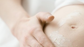 mujer untándose crema en la barriga