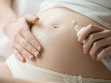 mujer untándose crema en la barriga