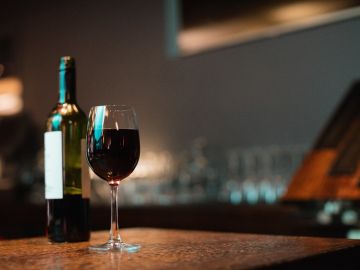 botella y copa de vino tinto sobre la mesa
