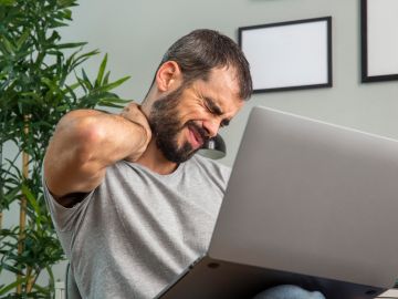 hombre frente a la computadora con dolor muscular