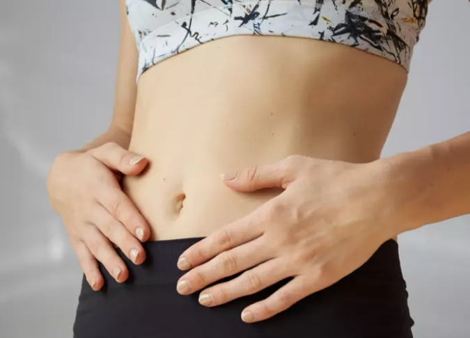 mujer tocándose el abdomen