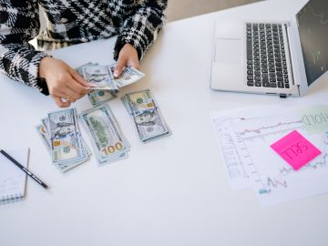 mujer contando billetes de 100 dólares