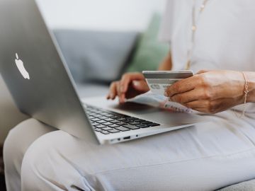 mujer con computadora y tarjeta de crédito