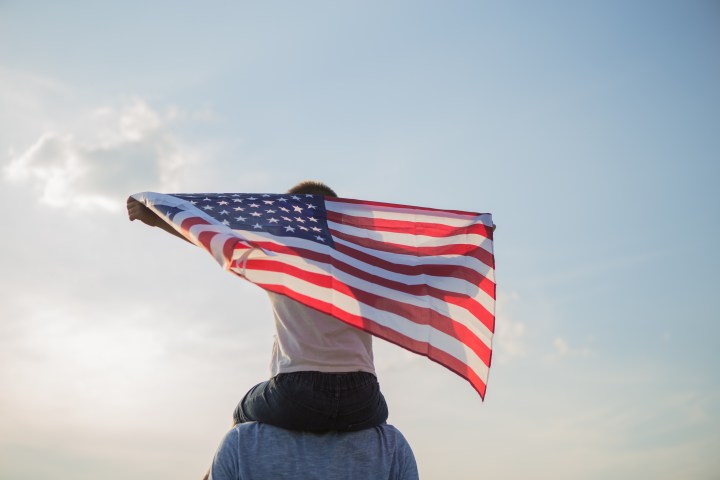 niño sobre los hombros de papa con bandera de estados unidos