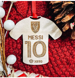 Añade un toque deportivo a tu árbol de Navidad con el encantador Ornamento de Fútbol Miami de Etch Society, hecho a mano y grabado con láser en madera de abedul. Un regalo perfecto para los fanáticos del fútbol.