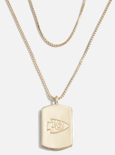 Sumérgete en el espíritu del fútbol con el collar BaubleBar Chief de Erin Andrews. Presentando un colgante versátil con el logo de los Chiefs en un lado y "Chiefs Kingdom" en el otro, este accesorio a $44 se destaca por su moderno cierre de mosquetón y cadenas en capas, brindando funcionalidad y estilo.